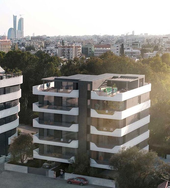 Modern residential building with numerous balconies and large windows against a city skyline.