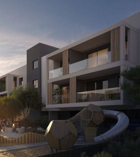 Modern gray building with balconies overlooks an outdoor sculpture and water feature.