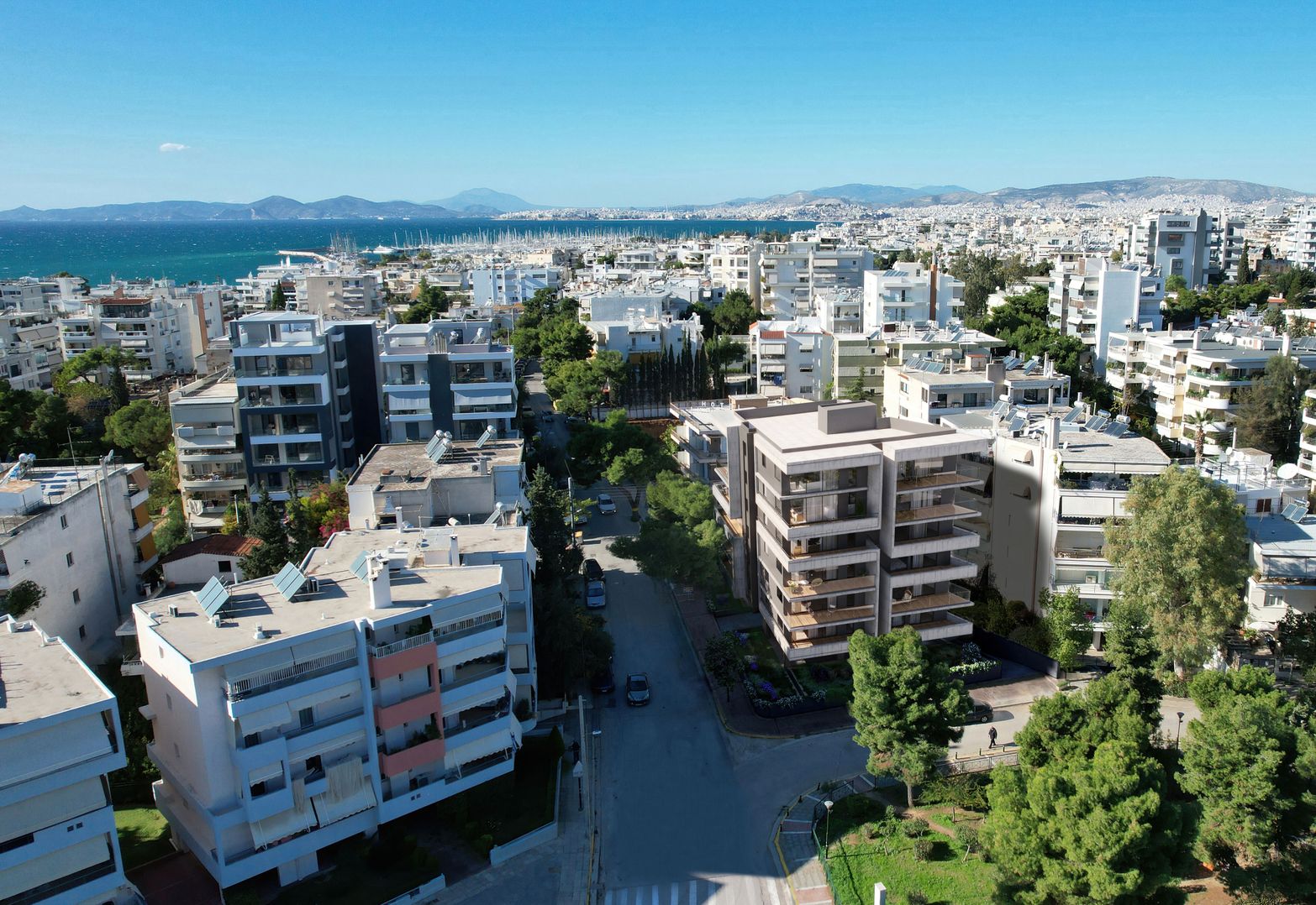 Aerial view of a coastal city with numerous apartment buildings under a clear blue sky.