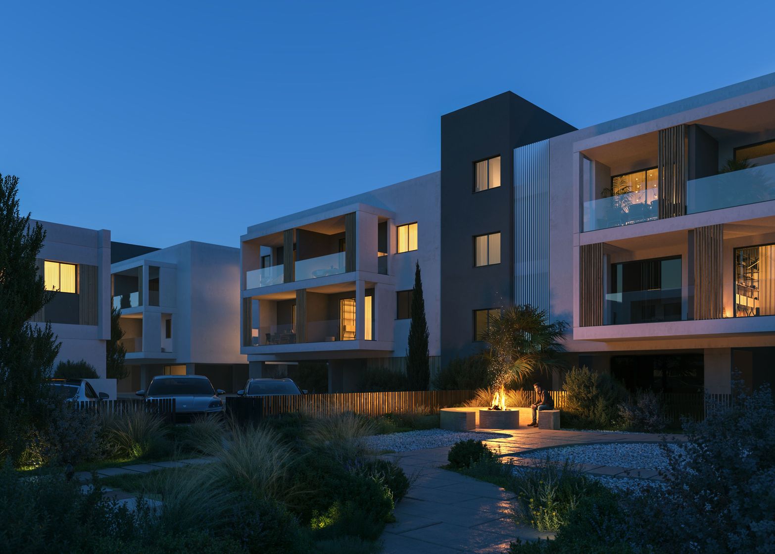 Modern residential buildings with illuminated balconies and pathways at dusk, showcasing contemporary architecture.