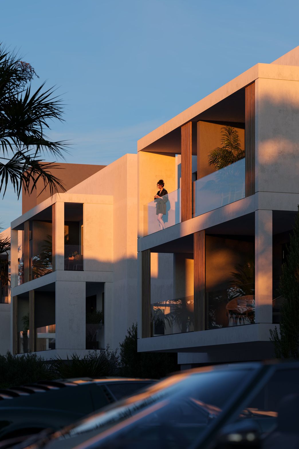 Modern white building with glass balconies, person on balcony, warm sunset glow.