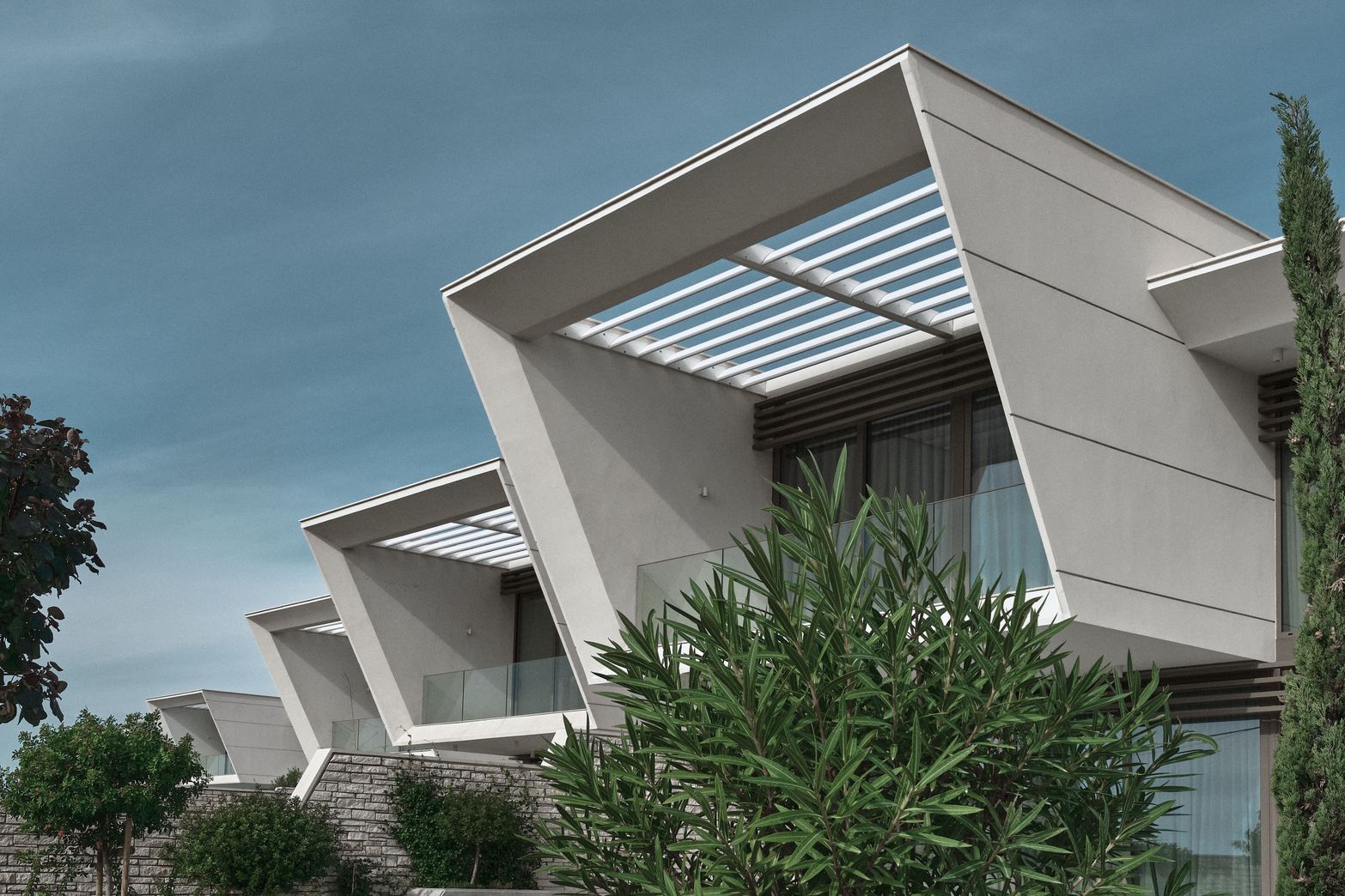 Sleek modern buildings with angular white facades and geometric roofs under a clear sky.