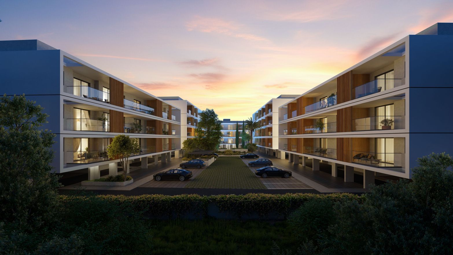Modern apartment buildings with balconies facing a landscaped courtyard at dawn.