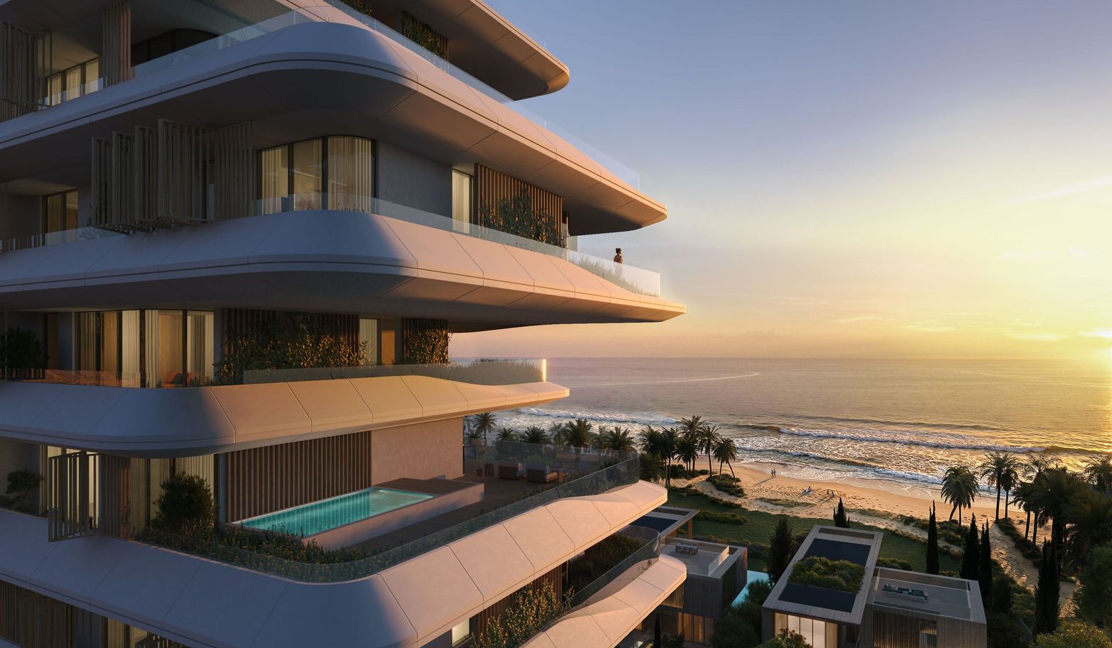 Modern building with curved balconies and pools overlooking a sunset beach.