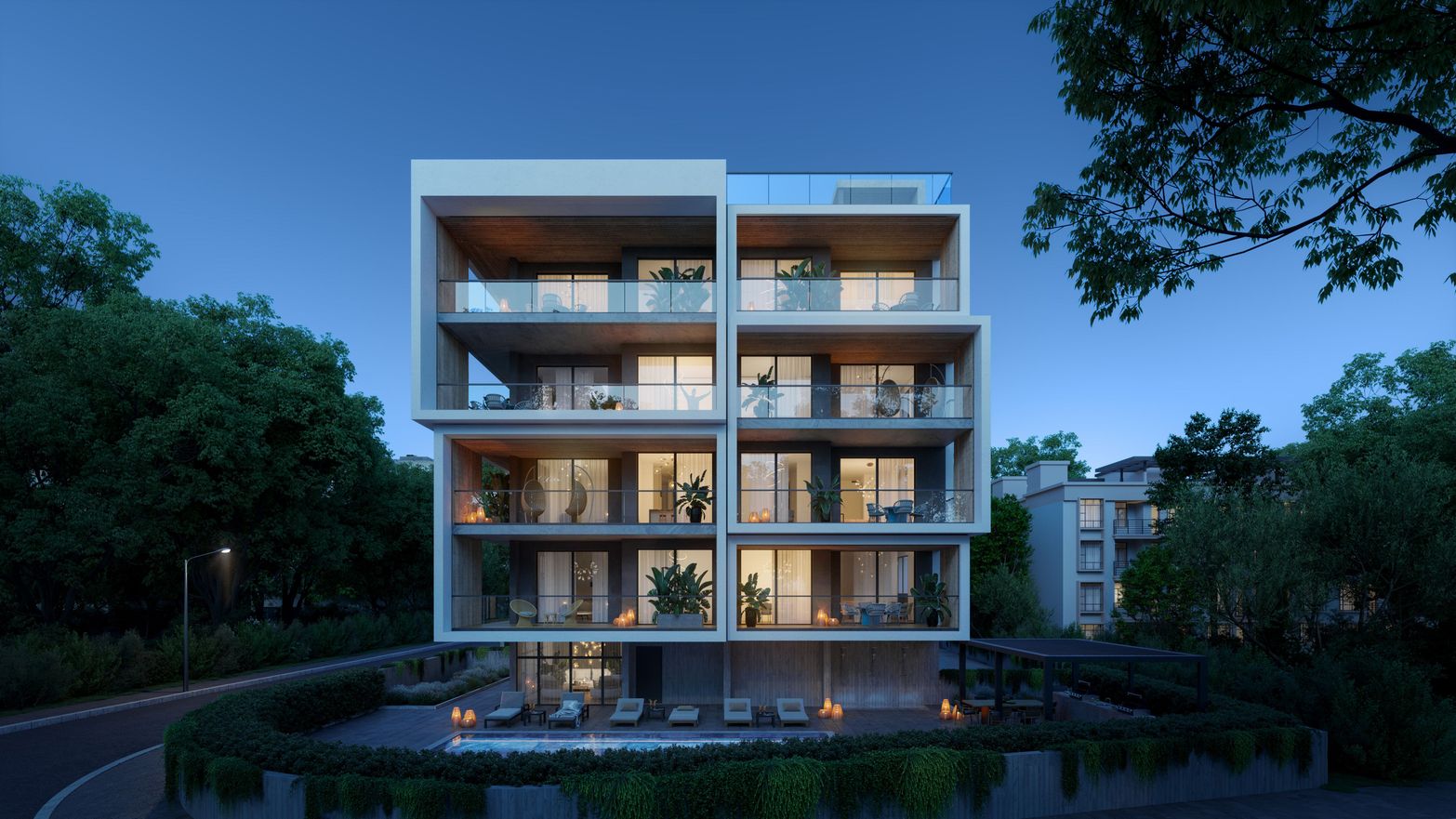 Modern apartment building illuminated at night with balconies and lush surrounding trees.