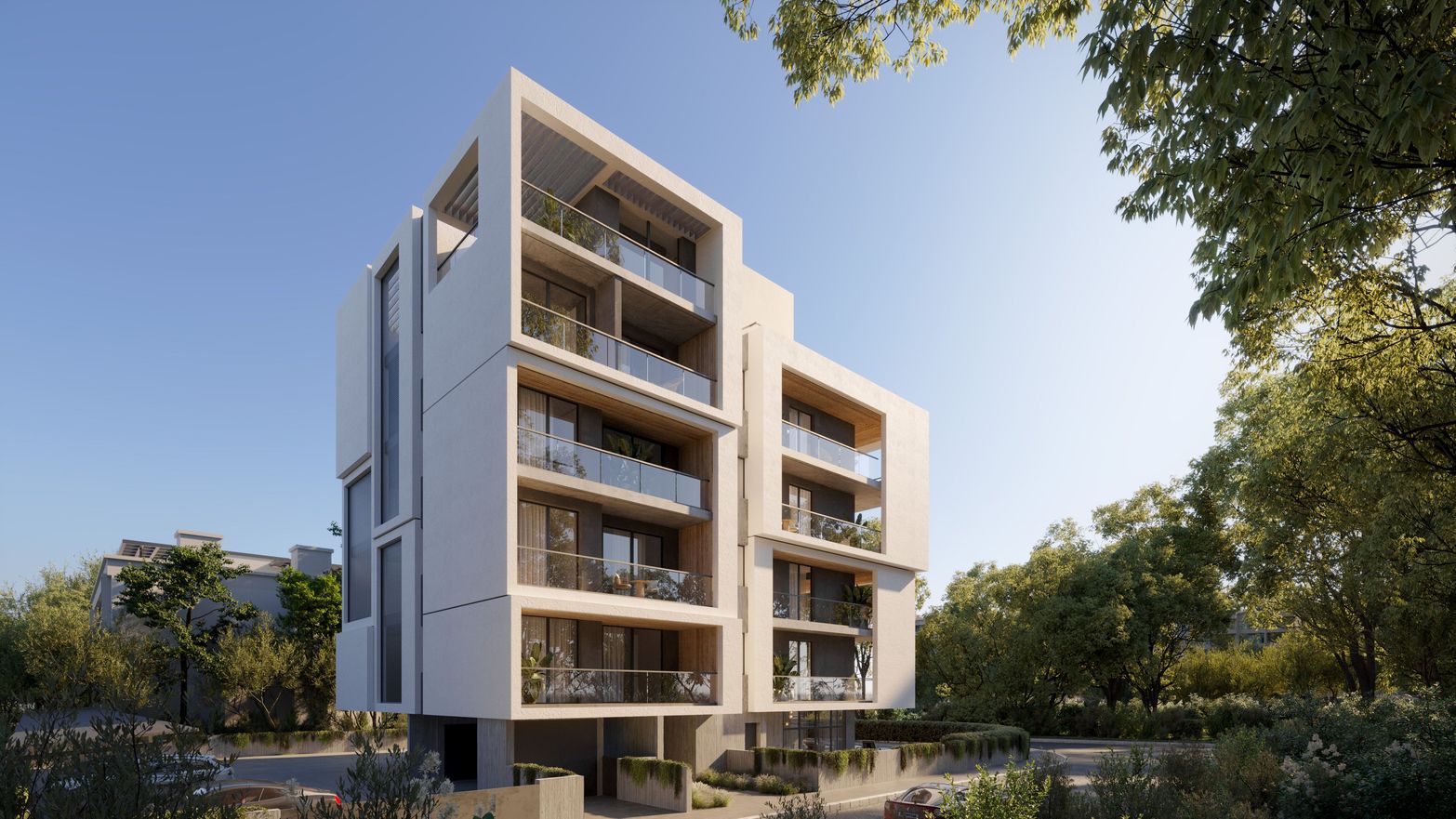 Modern light-colored apartment building with spacious balconies nestled among green trees.