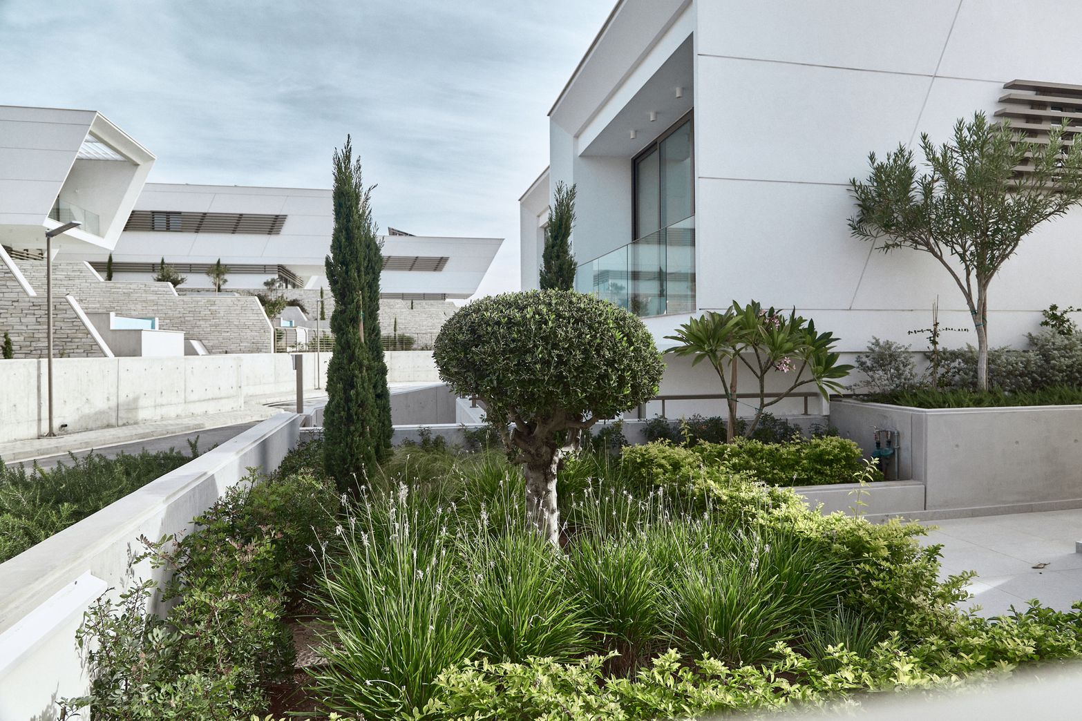 Modern white building with sharp lines surrounded by a well-maintained green garden.