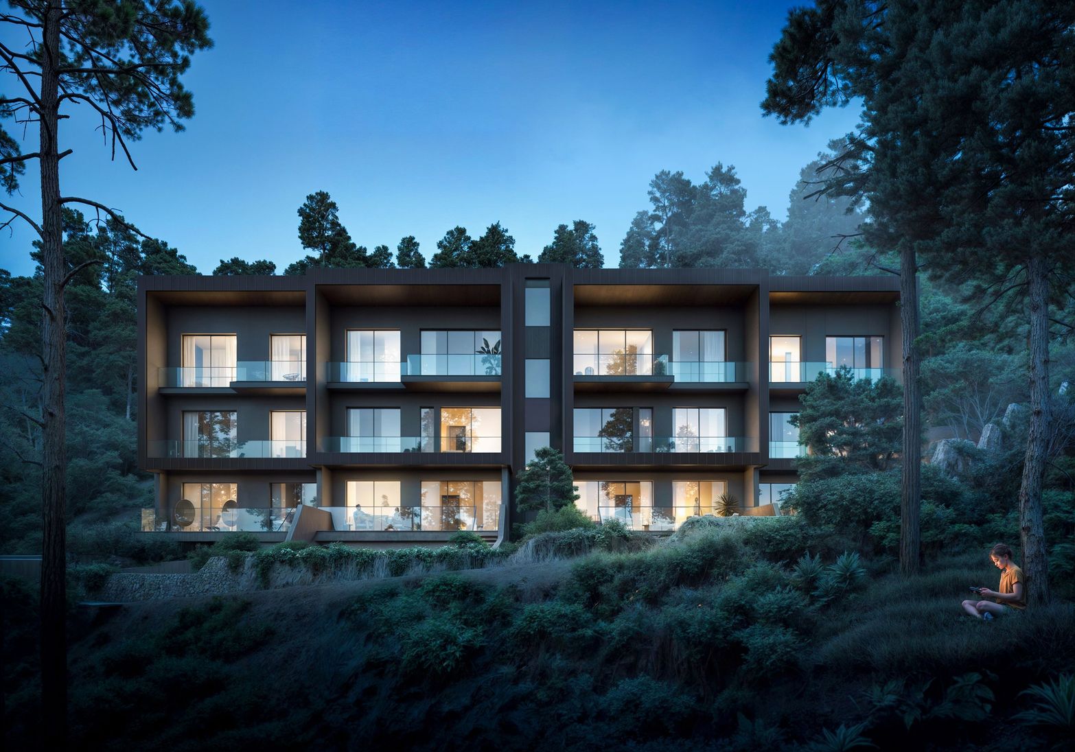 Modern multi-story building with illuminated windows nestled among dark trees at dusk.