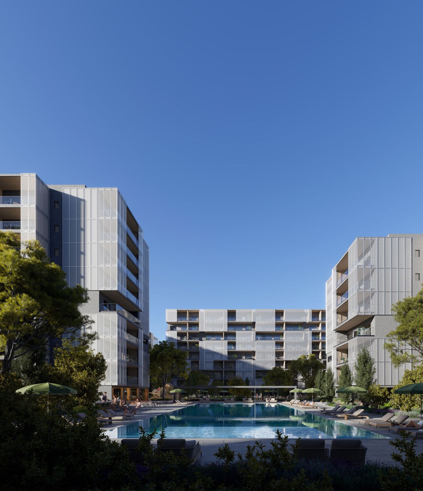 Modern apartment buildings overlook a large outdoor swimming pool under a clear blue sky.