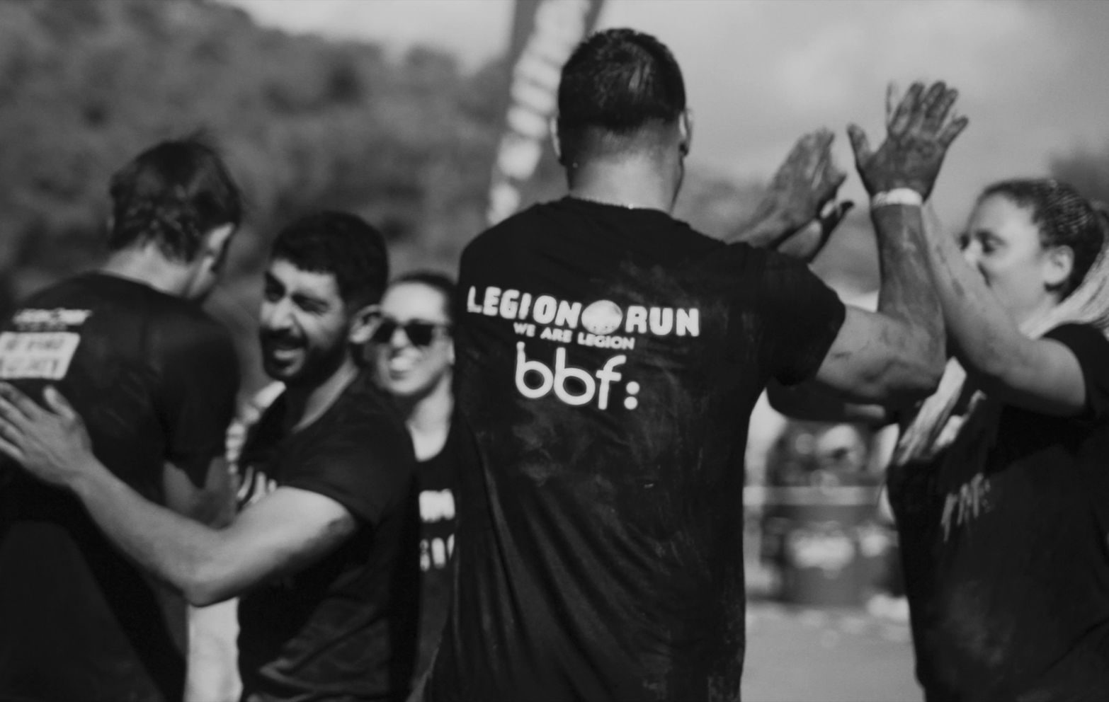 Participants high-fiving and celebrating after completing the Legion Run obstacle course event.