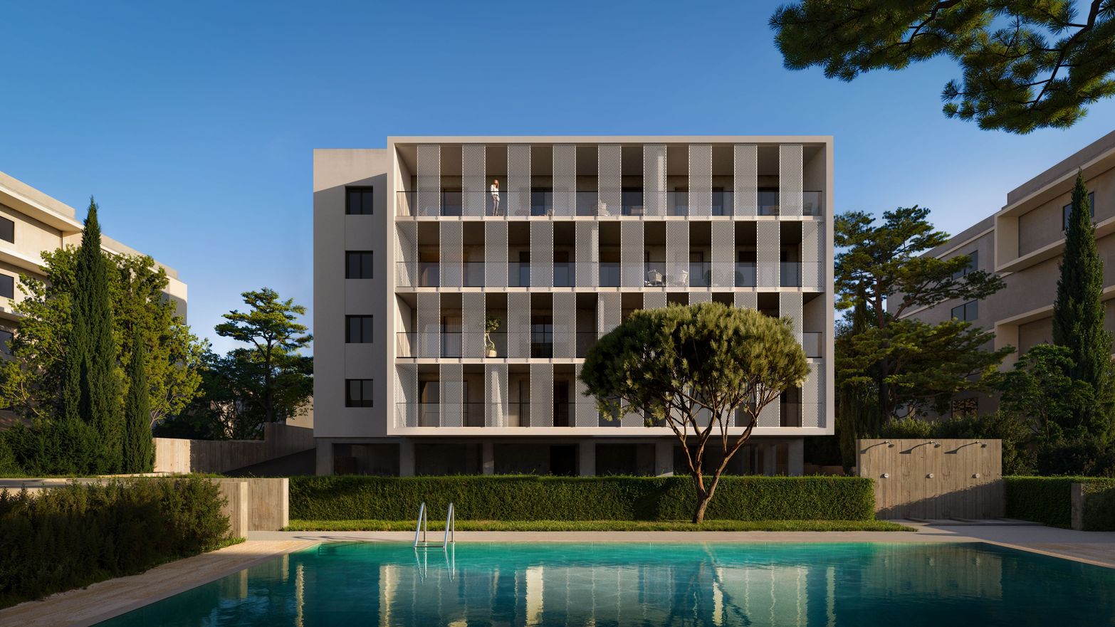 Modern white building with balconies overlooking a clear blue swimming pool and green landscaping.