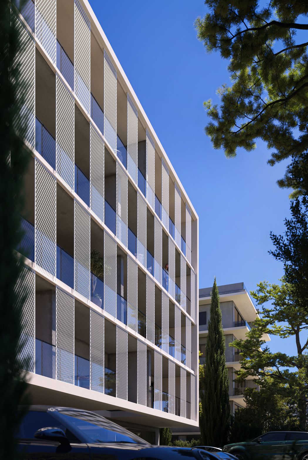 Modern multi-story building with glass balconies, contemporary architecture under a clear blue sky.