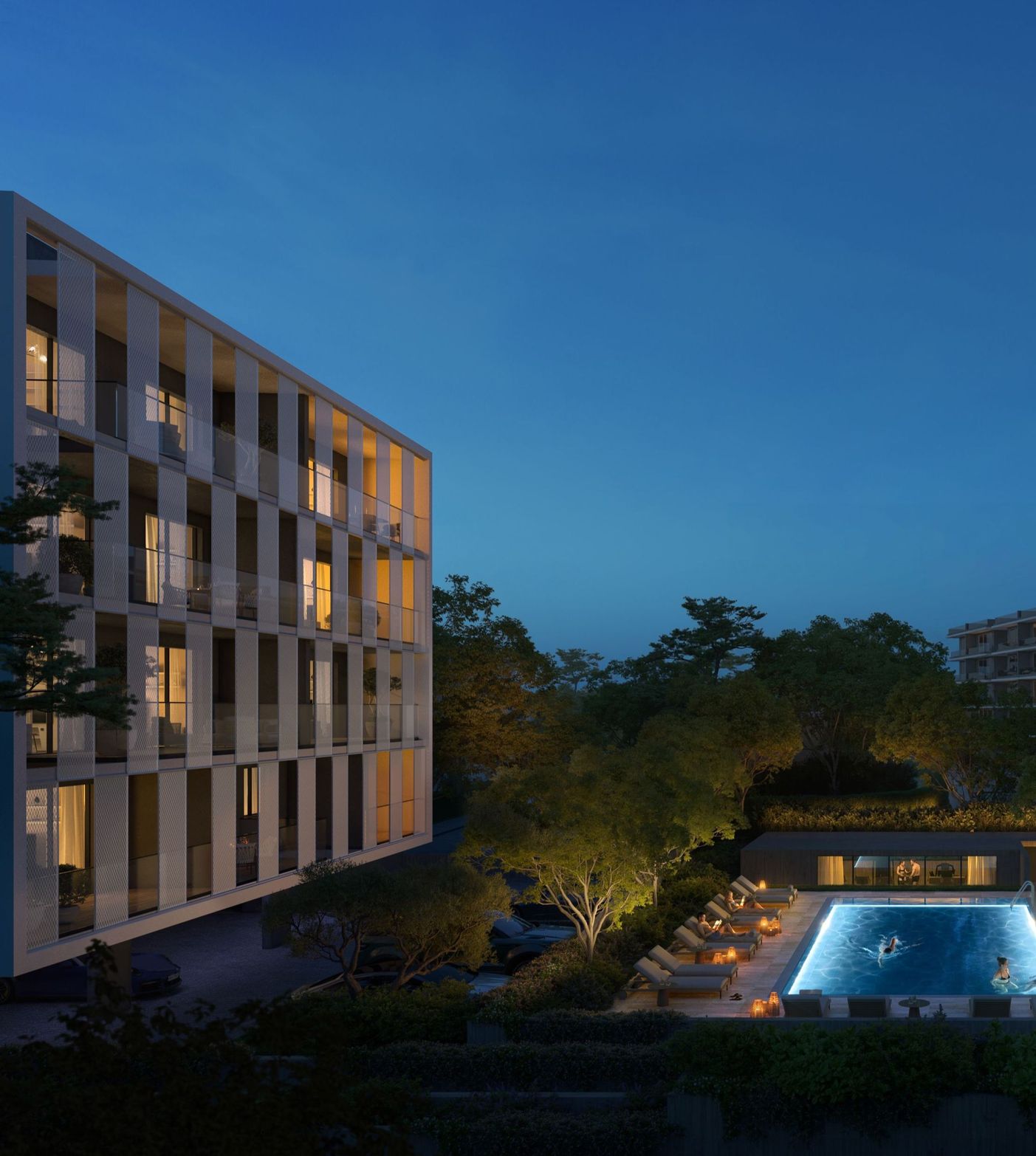 Modern building with lighted windows overlooks an illuminated swimming pool at dusk.