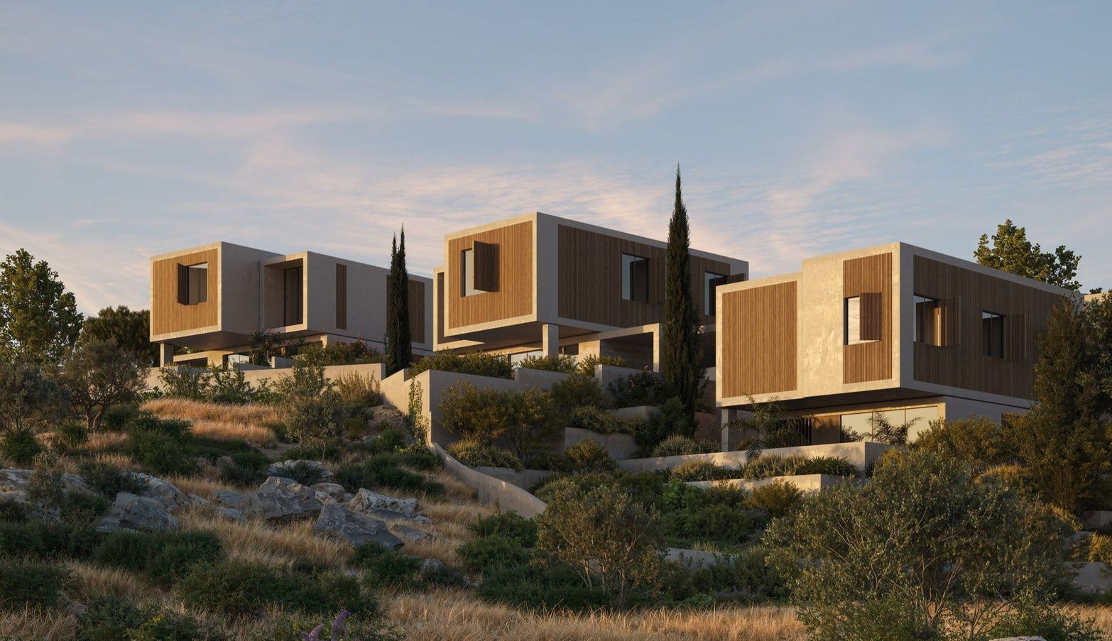 Modern cube-shaped houses integrated into a dry, sunlit hillside with sparse trees.